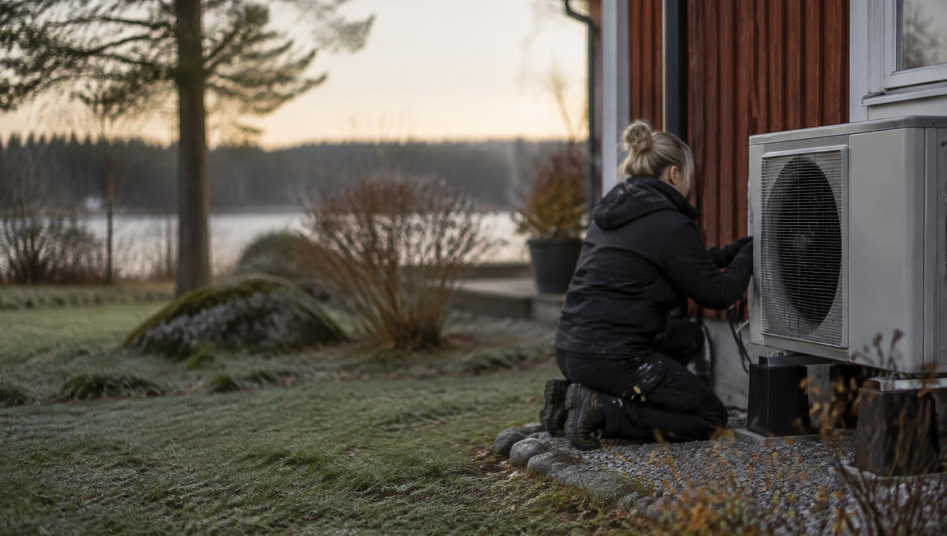 Illustrative image: a refrigeration technician at a heat pump on a cold morning.